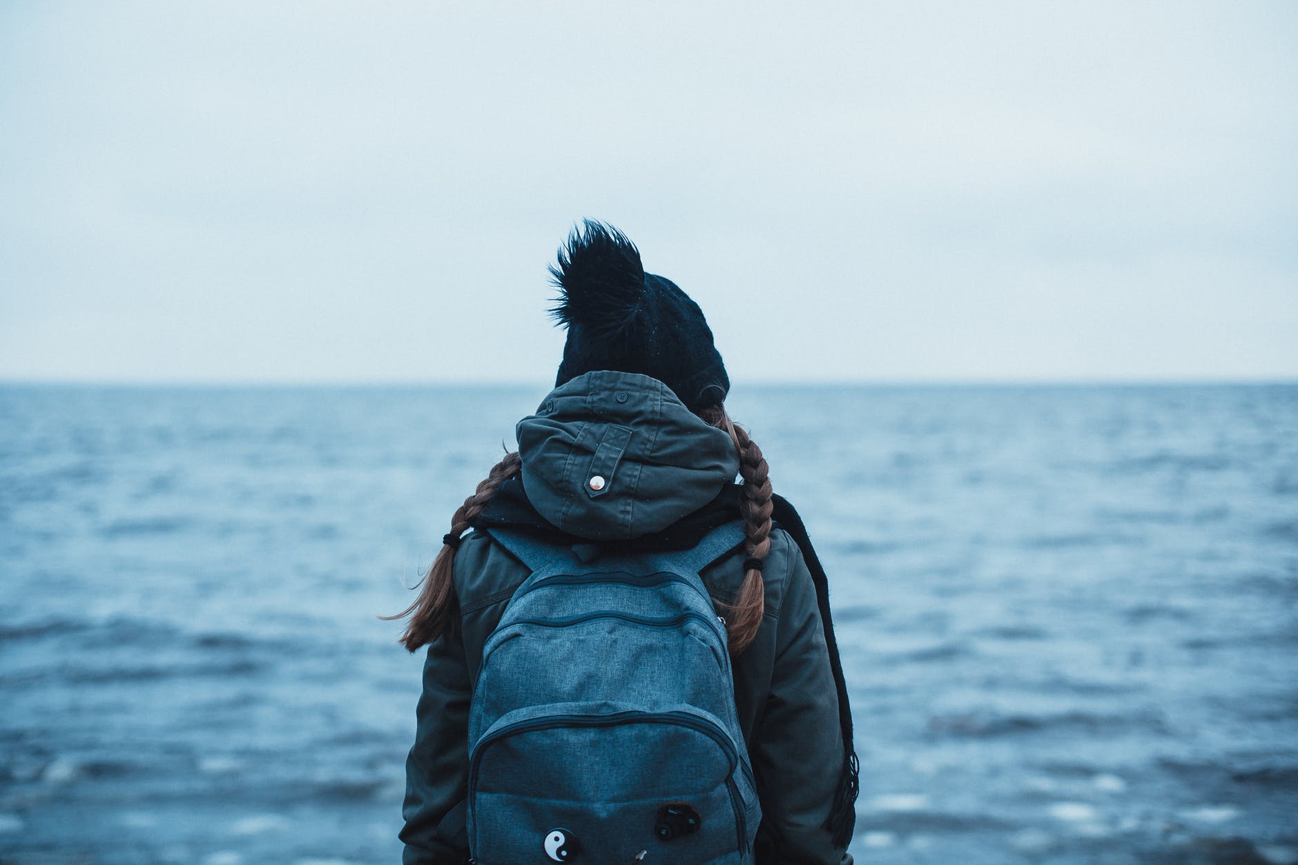 back view of a person carrying a backpack looking into the ocean
